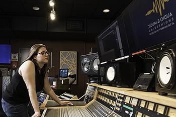 A person working the board in the control room of s sound studio.